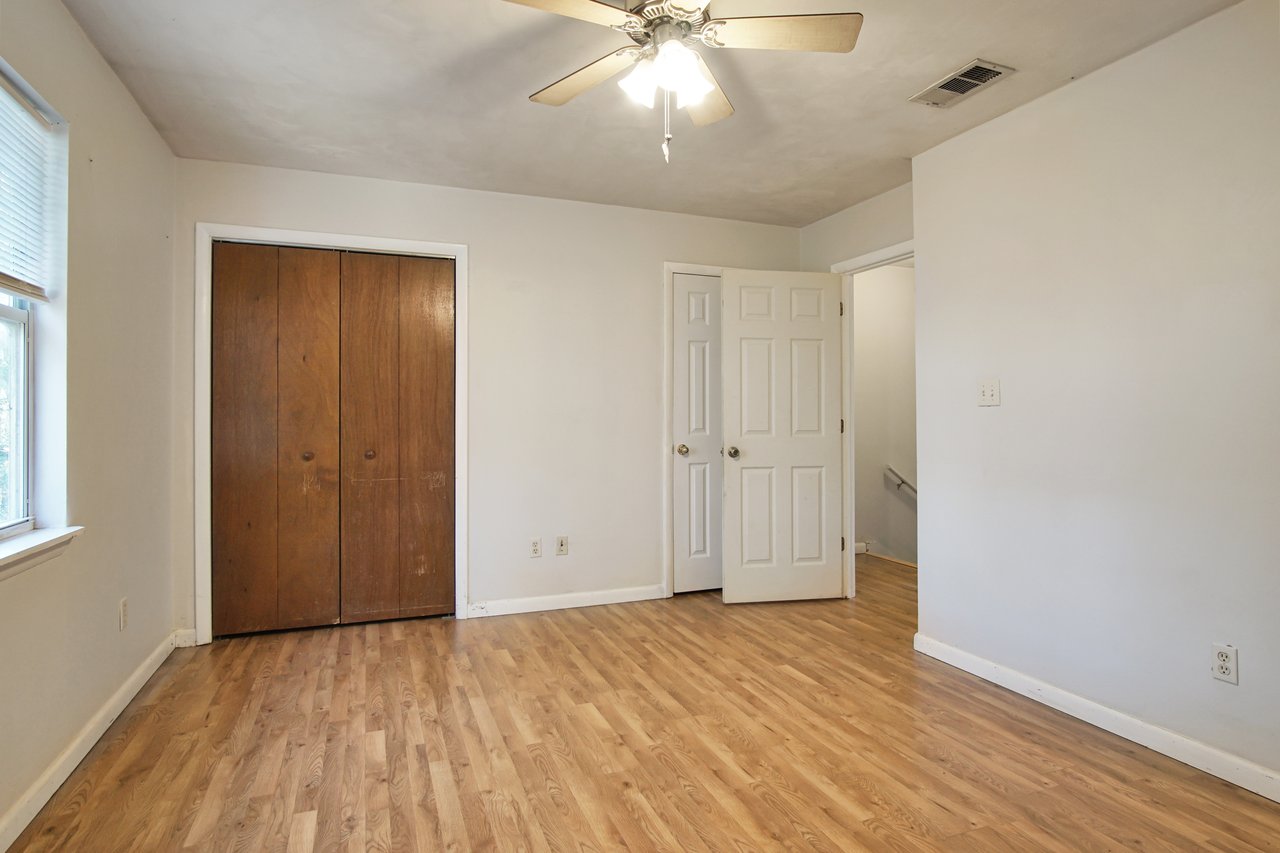 An empty room featuring hardwood floors and a ceiling fan, creating a spacious and airy atmosphere.