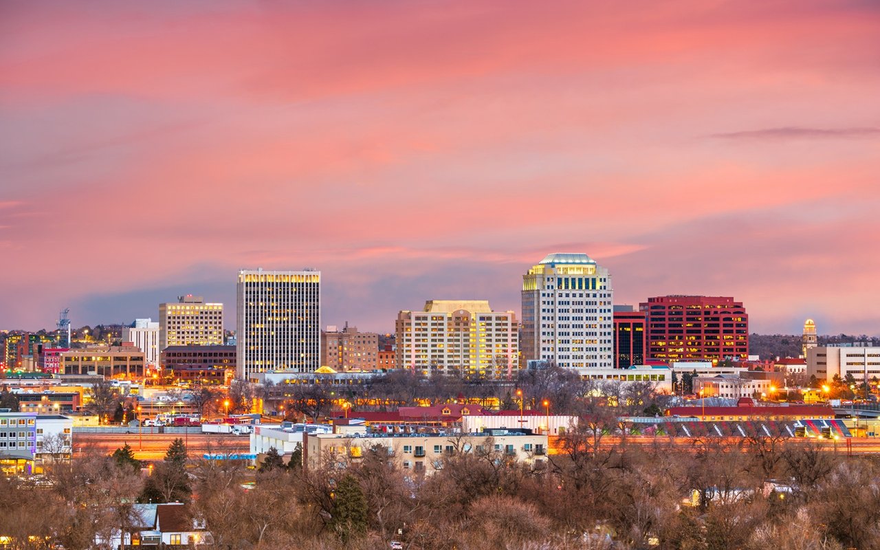 Downtown Colorado Springs skyline glowing beneath a pink sunset sky.