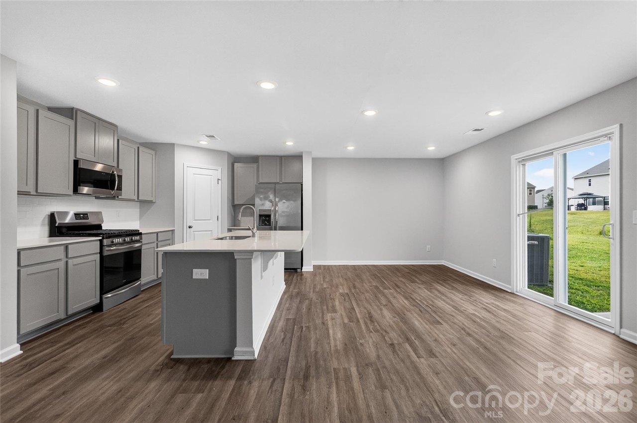 Open kitchen with gray cabinets, a white island, and sliding glass doors to the backyard.