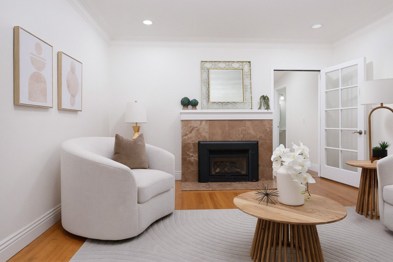 Staged living room with a tiled fireplace, curved white chair, and round wood coffee table.