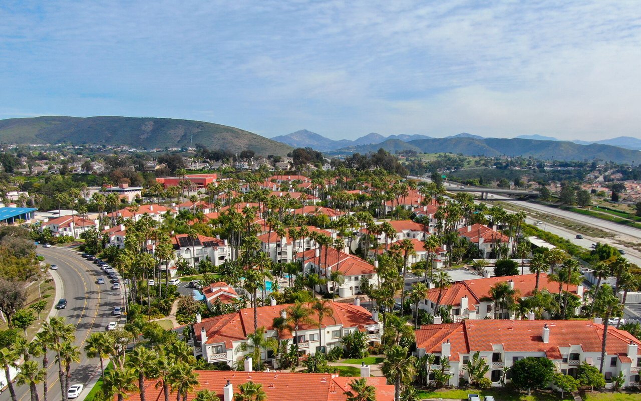 Escondido neighborhood of red-tile-roof homes and palm trees, with hills and mountains in the distance.