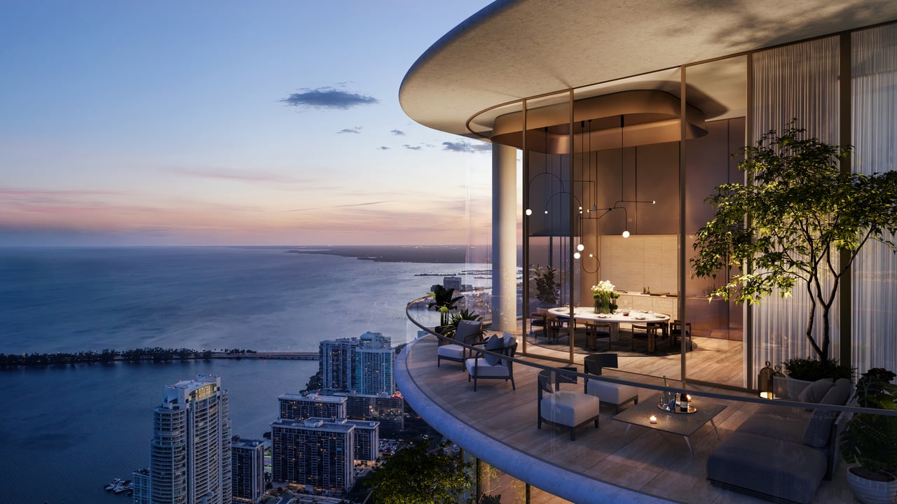 Luxury residence terrace overlooking Biscayne Bay, with a curved glass dining room and city views at dusk.