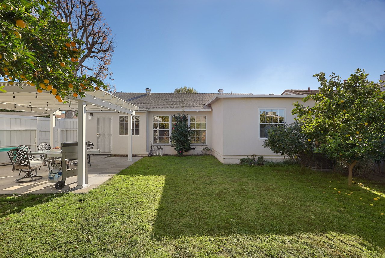 Rear view of home with landscaped yard, dual windows, and patio area at 17049 Baltar Street