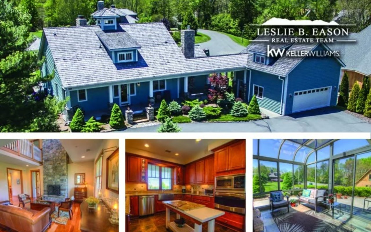 Blue home with landscaped grounds, attached garage, and a glass-enclosed sunroom.