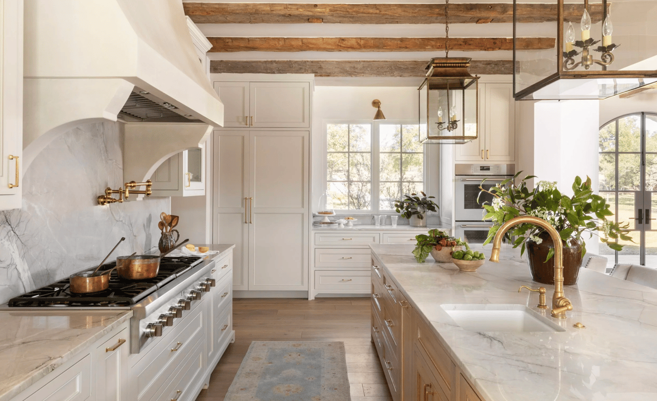 Maddalena Ranch kitchen with marble island, brass faucet, and exposed timber ceiling beams.