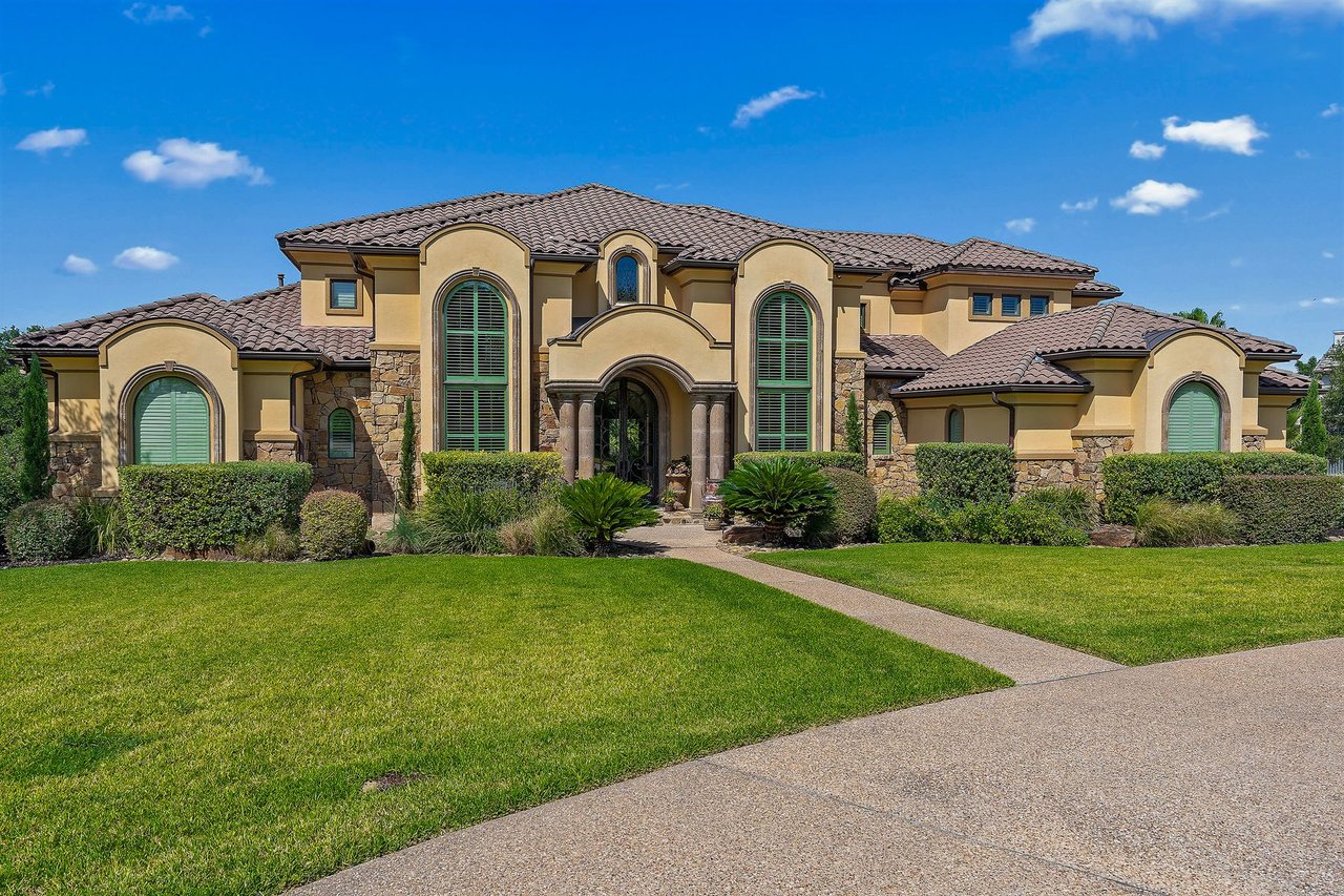 Front elevation of the stone and stucco home with a tile roof and arched entry at 25715 Cliff Circle, Lakecliff on Lake Travis, Spicewood, Texas.