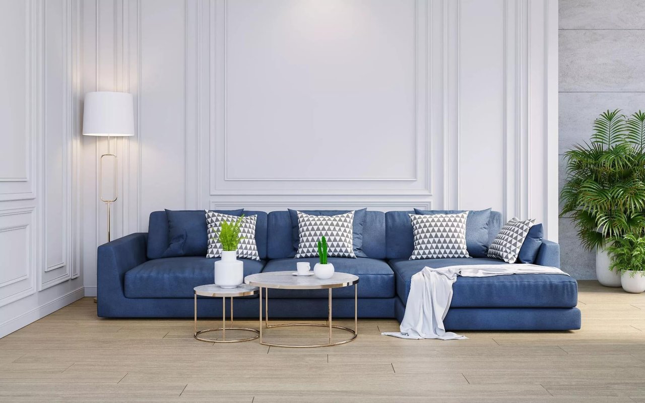 Living room with a blue sectional sofa, round coffee tables, and white paneled walls.
