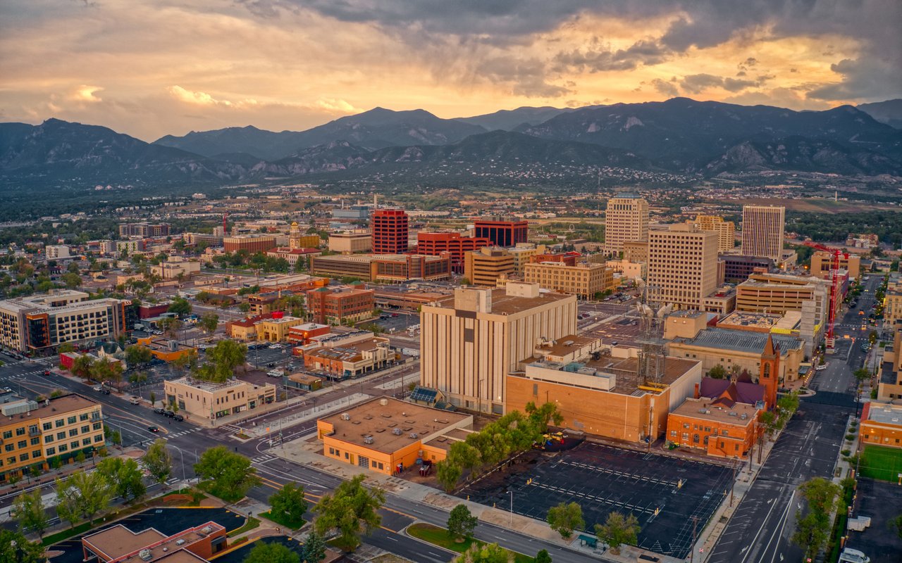 Downtown Colorado Springs and the Rocky Mountains beneath a golden sunset.