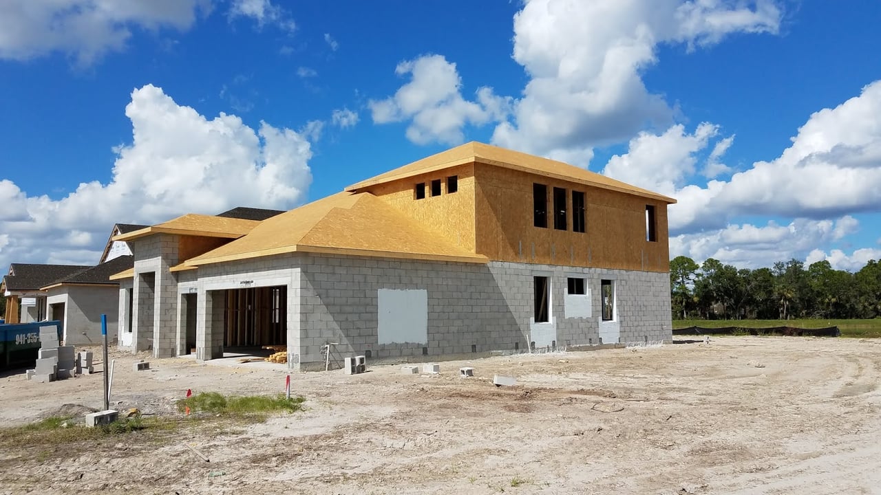 Two-story house under construction with block walls and exposed wood sheathing.