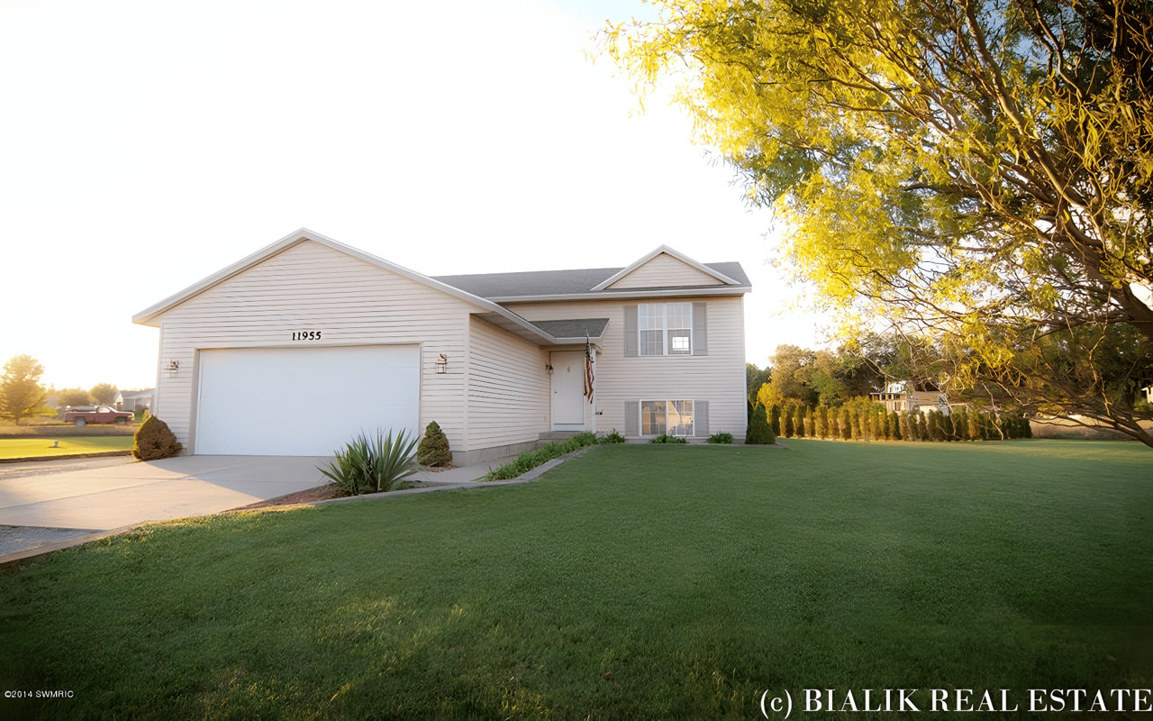 Light-colored Rockford home with attached garage, broad lawn, and golden-hour tree canopy.