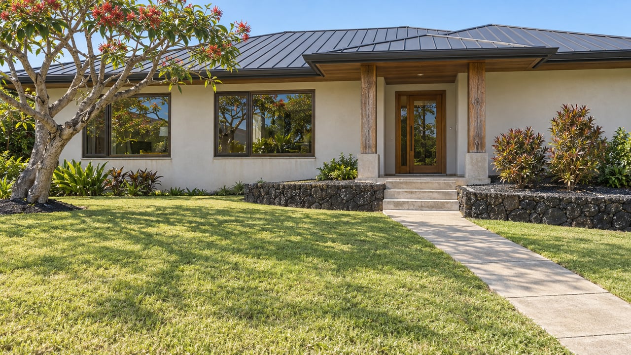 Single-story home with a deep sunlit lawn, dark hipped roof, sheltered timber entry, and black stone retaining wall.