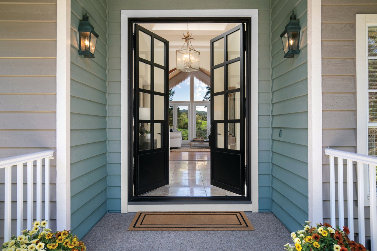 Home entry with open black-framed double doors, paired lanterns, and a view into the living room.