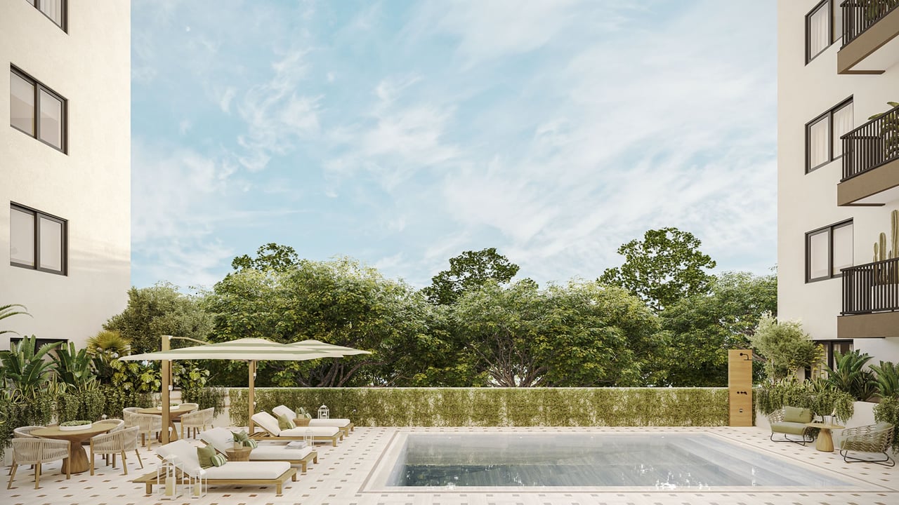 Residential pool terrace with sun loungers, dining tables, umbrellas, and lush greenery between modern buildings.
