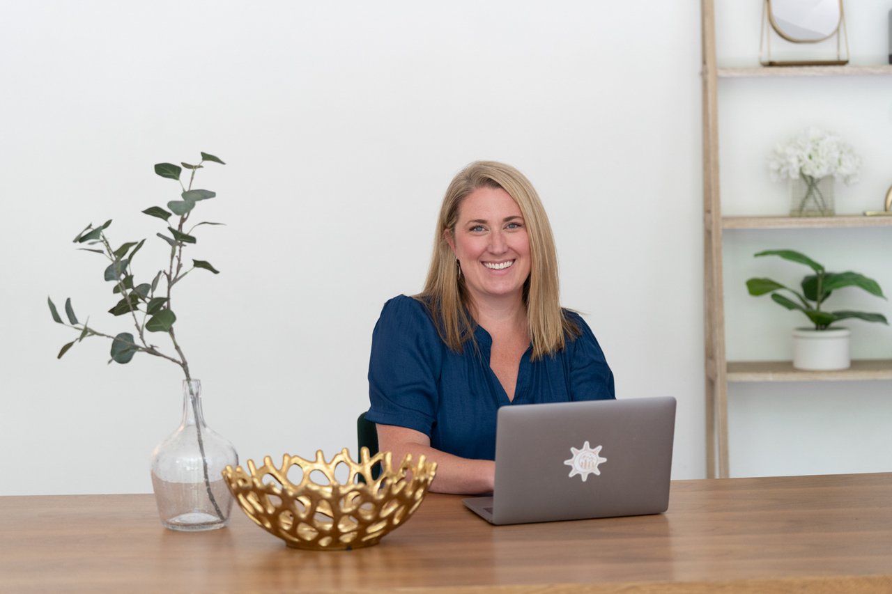 Denver real estate agent Kathryn Tighe sitting at a desk with a laptop assisting homebuyers with real estate contracts