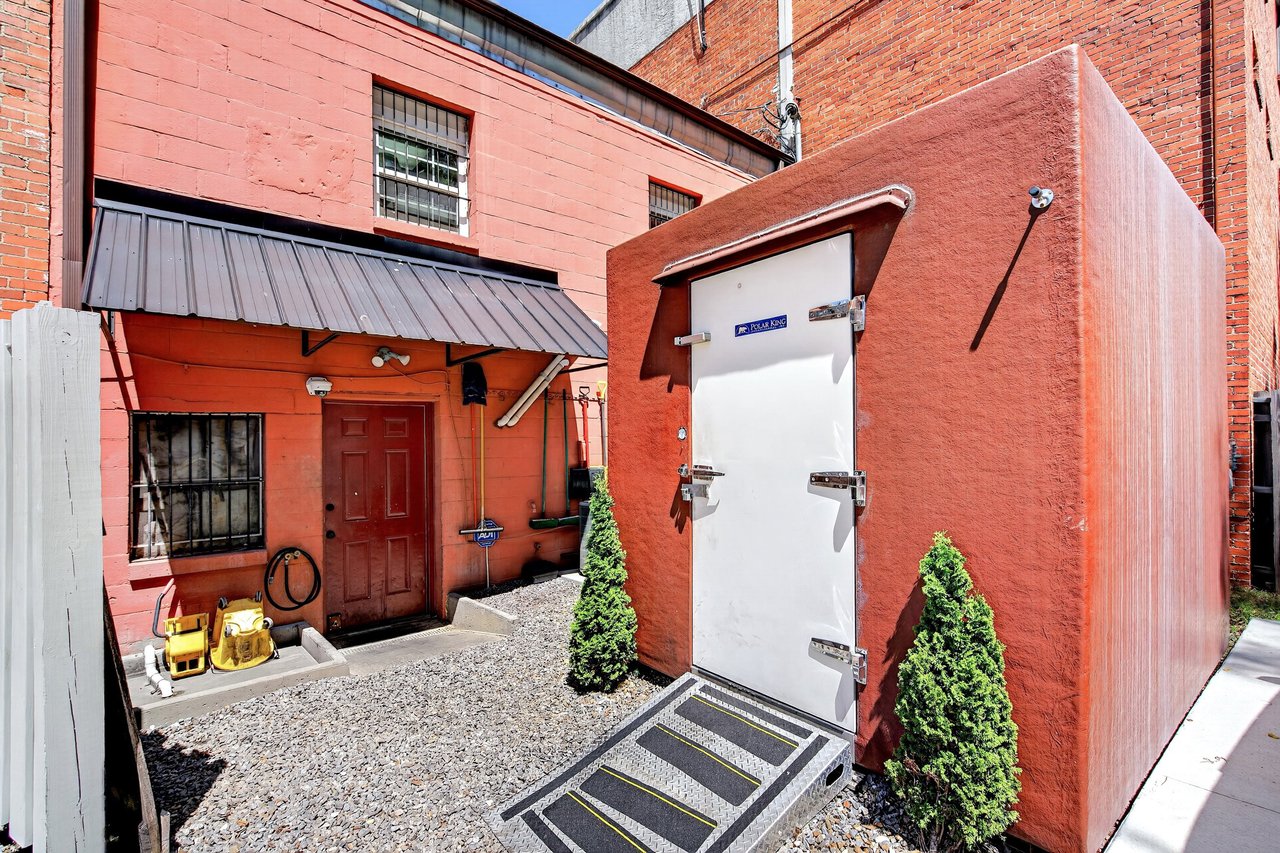 Restaurant service area with a white walk-in cooler door and red-brick walls.