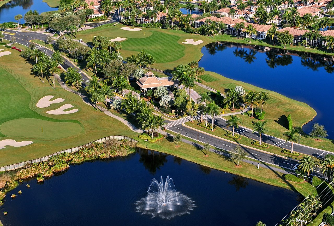 Aerial view of a golf course community with lakes, homes, and a fountain.