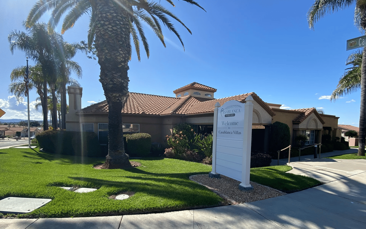Scenic suburban streetscape with palm trees and Mediterranean-style home in the Heritage Lake master-planned community of Menifee, California.