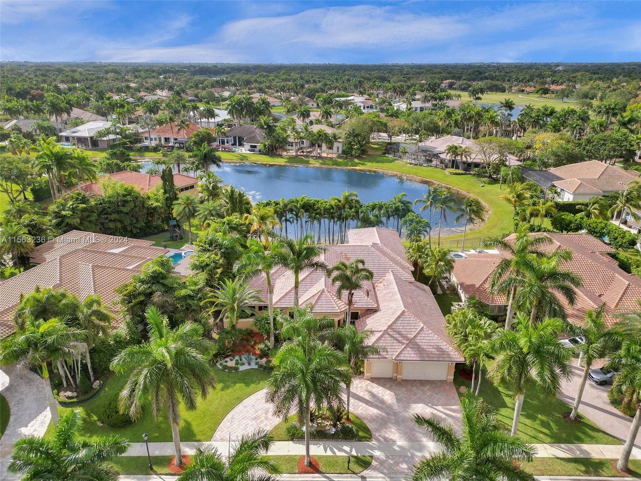 Aerial view of palm-lined homes surrounding a small lake.