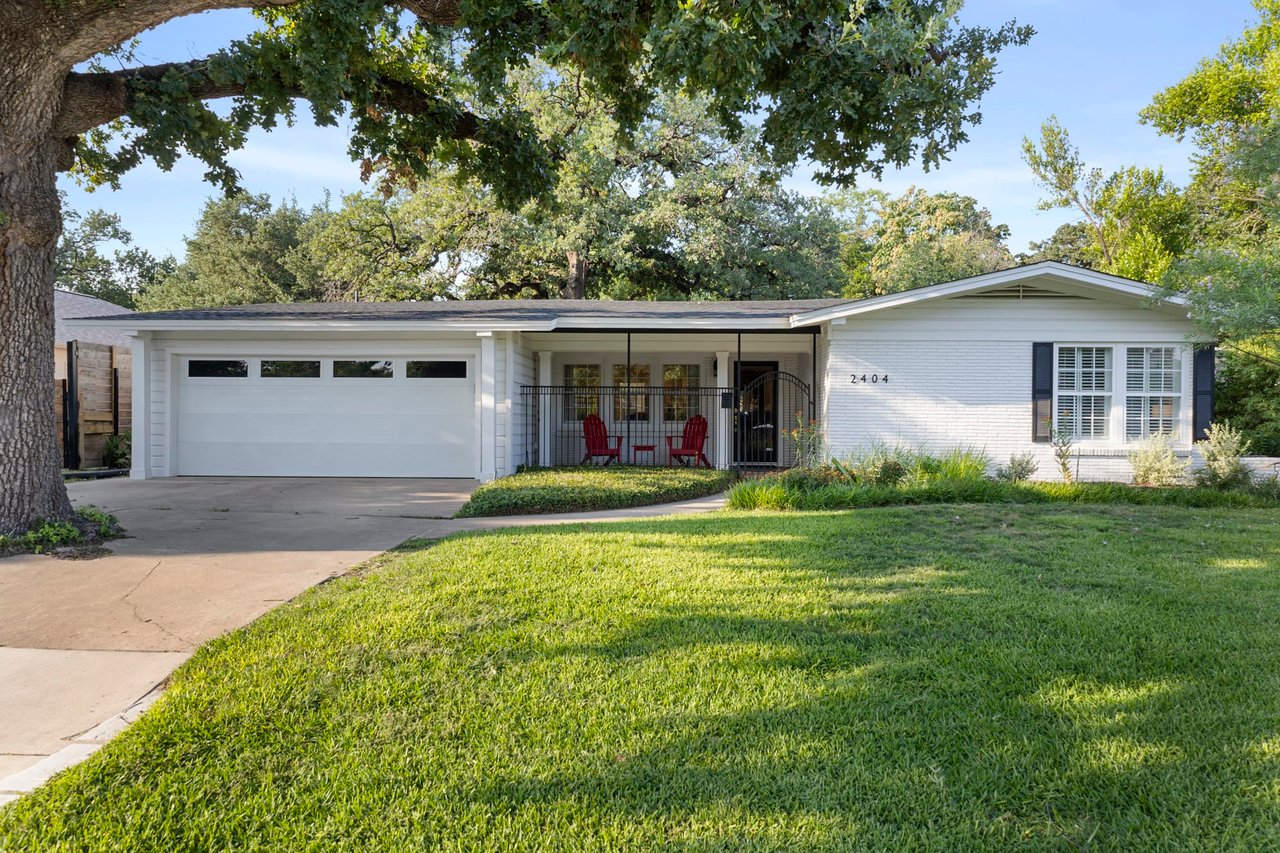 Daylight front elevation of the mid-century modern brick home with attached garage, 2404 Westover Rd, Tarrytown, Austin.