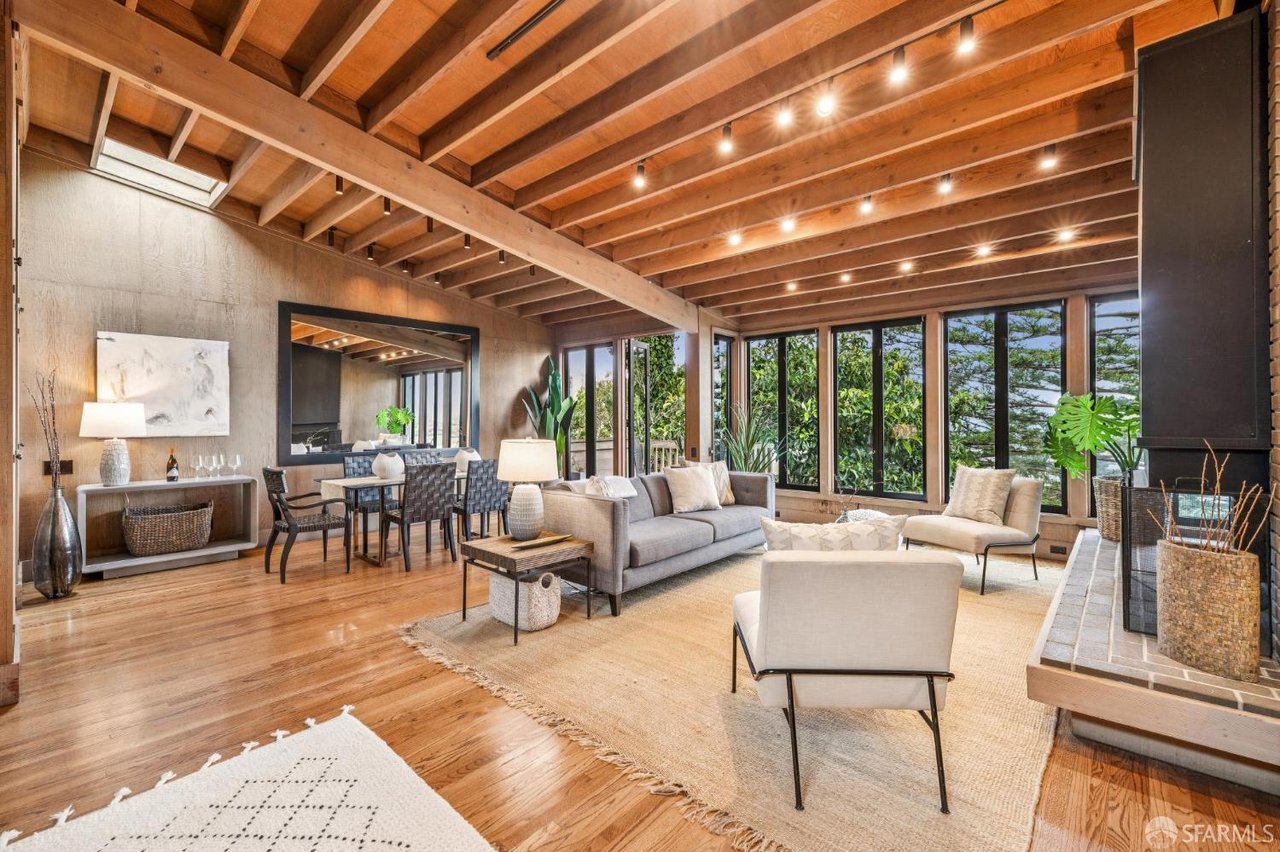 Open living room with exposed wood beam ceiling, hardwood floors, and large windows in a San Francisco home sold at 3616 21st St.
