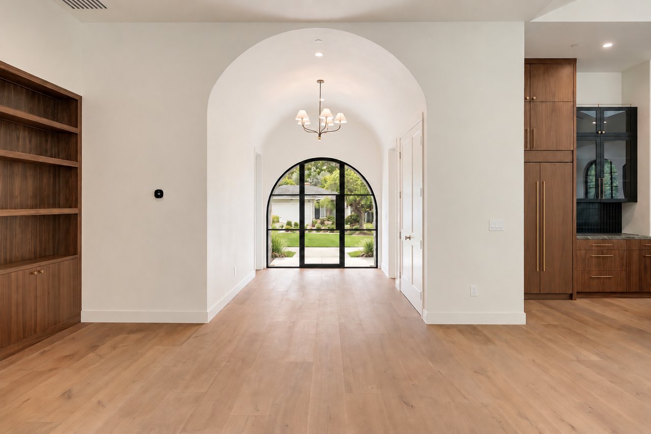 Entry foyer with an arched glass door, walnut built-ins, and light wood floors.