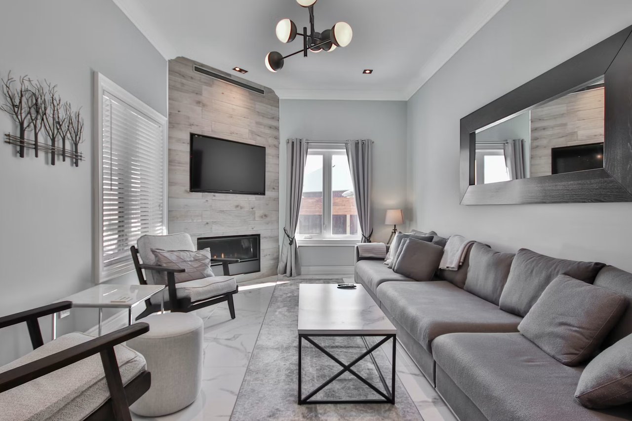 Modern living room with a gray sectional, marble-look coffee table, fireplace and wall-mounted television.