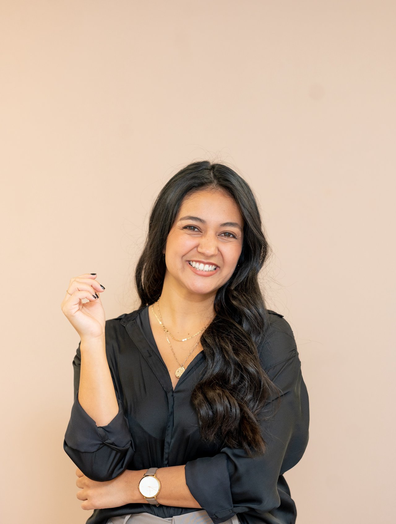 Khrista Gonzalez smiling in a black blouse, with long dark hair and crossed arms.