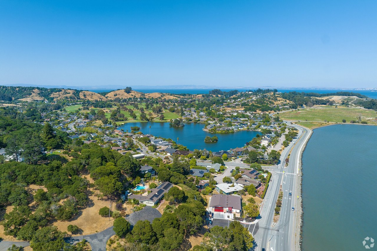 Aerial view of Glenwood, San Rafael, showing homes around a lagoon beside the bay and coastal road.