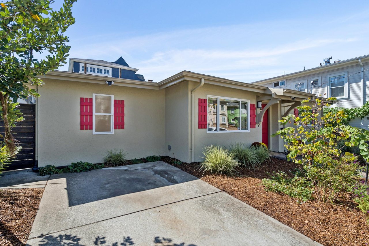 Home exterior with red shutters and entry door, a concrete driveway, and landscaped planting beds.