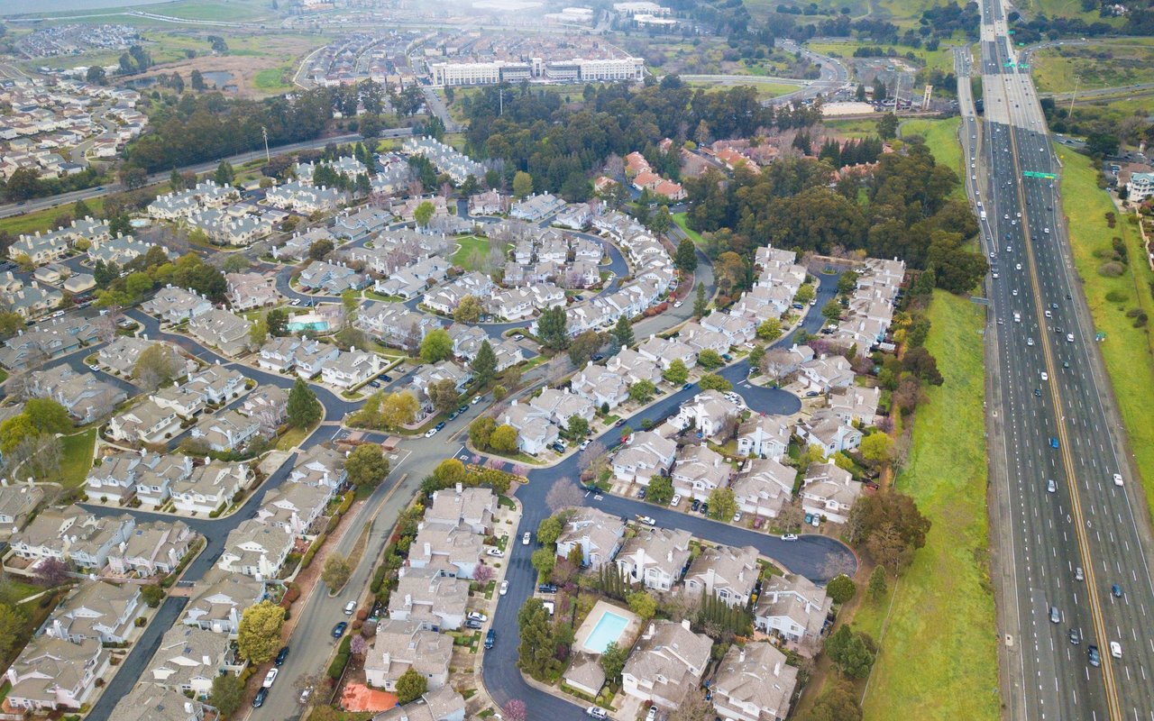 Aerial view of homes along curving streets beside a major freeway.