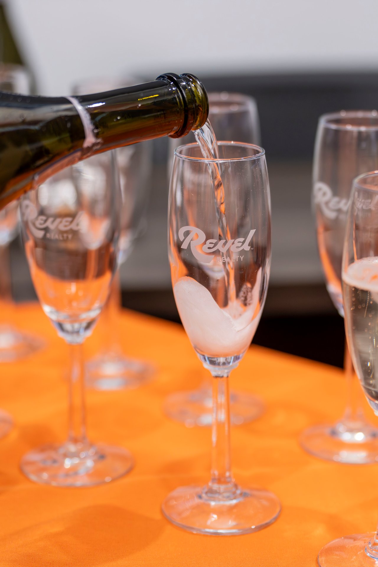 Champagne being poured into Revel Realty champagne glass
