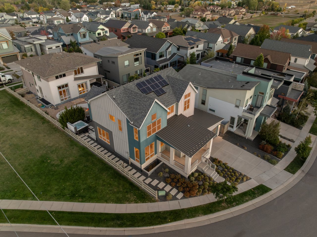 Aerial view of the home with rooftop solar panels and surrounding streets