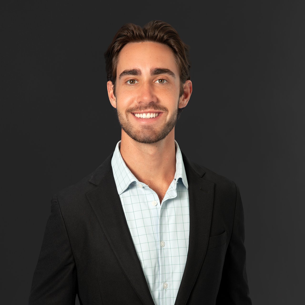 Jack Reynolds smiling in a black blazer and pale checked shirt.