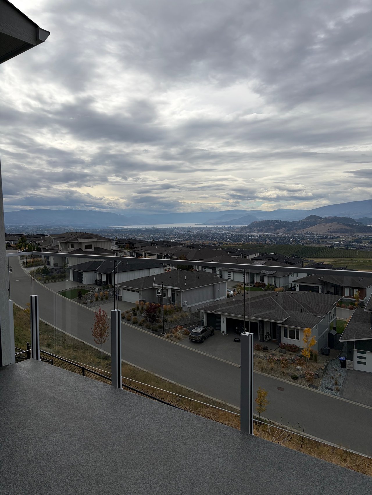 Tower Ranch homes overlook Kelowna, Okanagan Lake, and distant mountains from a glass-railed terrace.