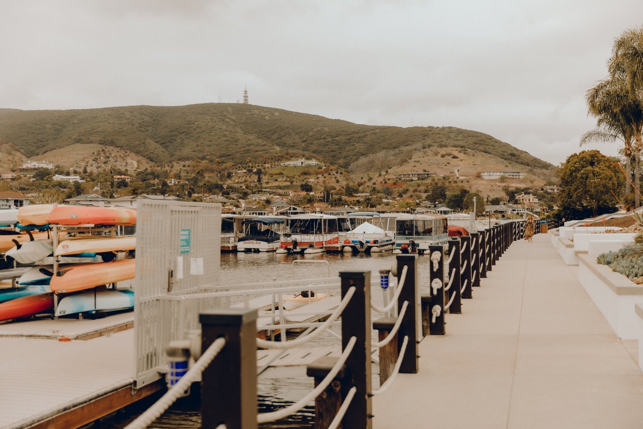 Agency West by Amy Ali showcases Southern California luxury real estate with a marina waterfront view and coastal hills at sunset