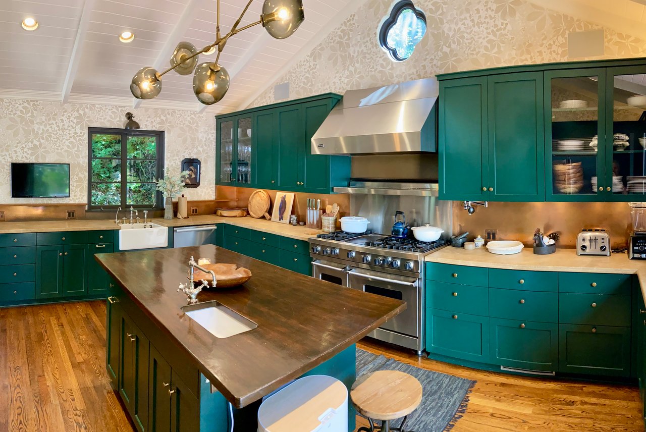 Professionally staged modern kitchen with green cabinetry, stainless steel appliances, and brass lighting fixtures showing how fresh finishes and proper staging increase home appeal for buyers