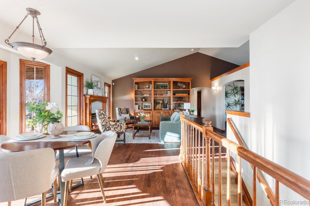 Open-plan living and dining area with a fireplace, built-in shelving, and sunlit hardwood floors.