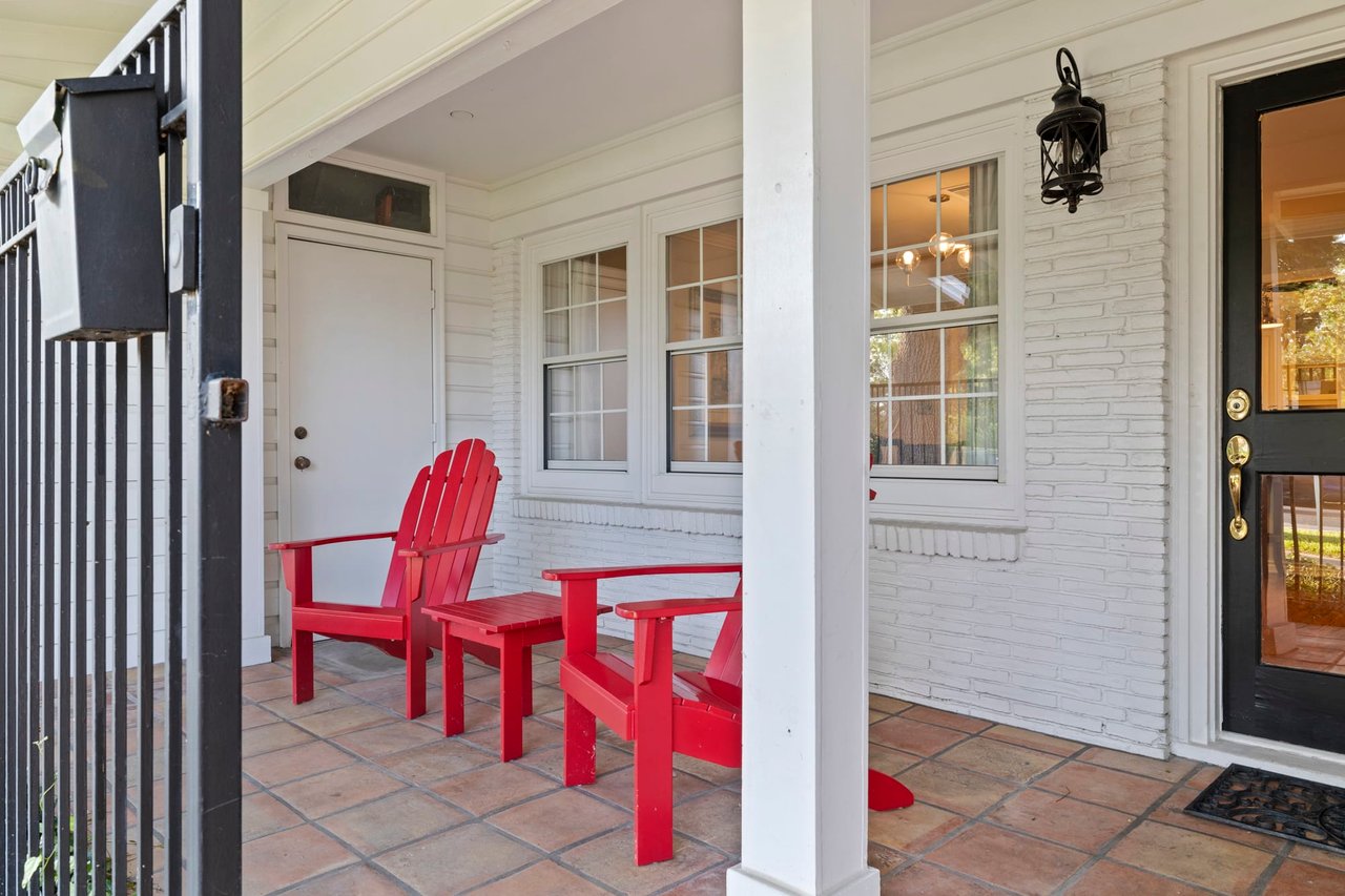 Front porch detail with red Adirondack chairs at this Tarrytown home.