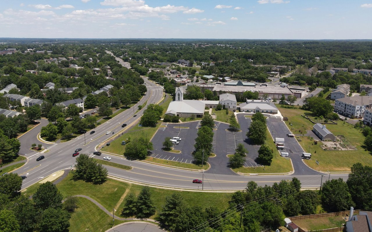 Aerial view of Highland City with tree-lined streets and a church beside a large parking lot.