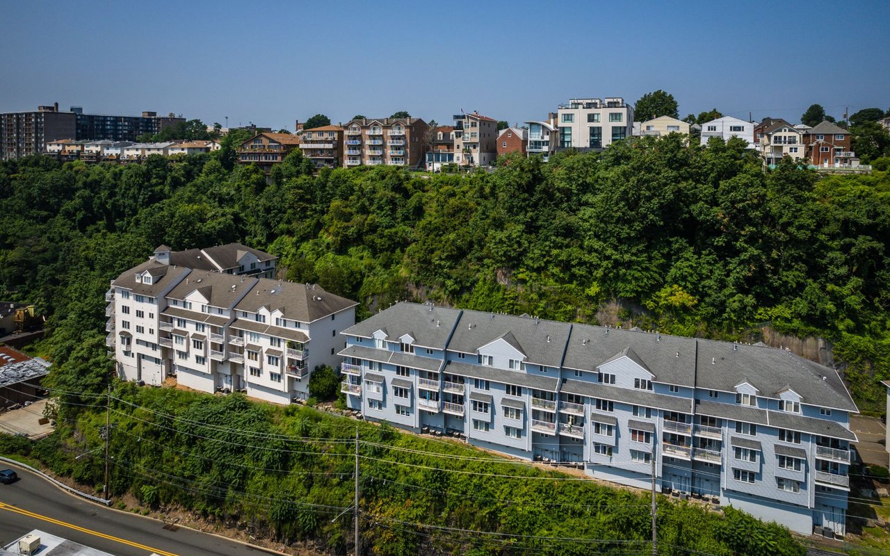 Aerial view of Goldcoast residences beside a wooded bluff, with homes lining the ridge.