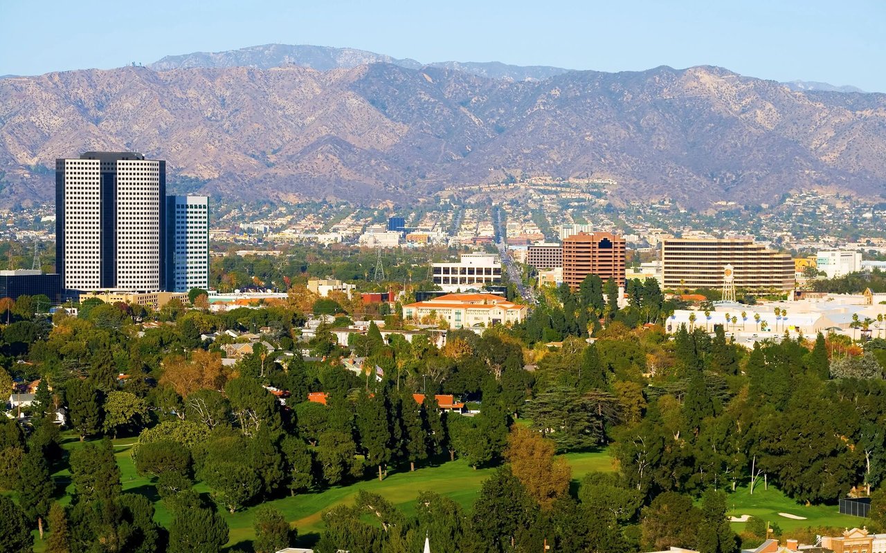 Urban neighborhood and golf course below a broad mountain range.