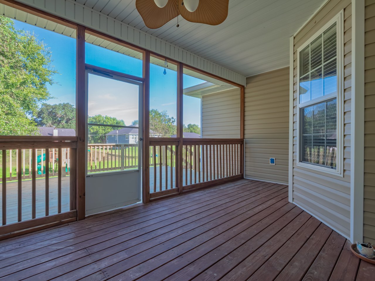 Screened back porch with a wood plank floor, ceiling fan, and views of the yard.