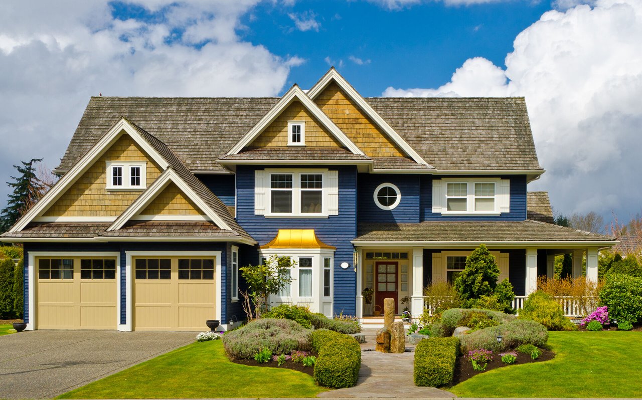 Blue two-story house with yellow gables, a double garage, and landscaped front garden.