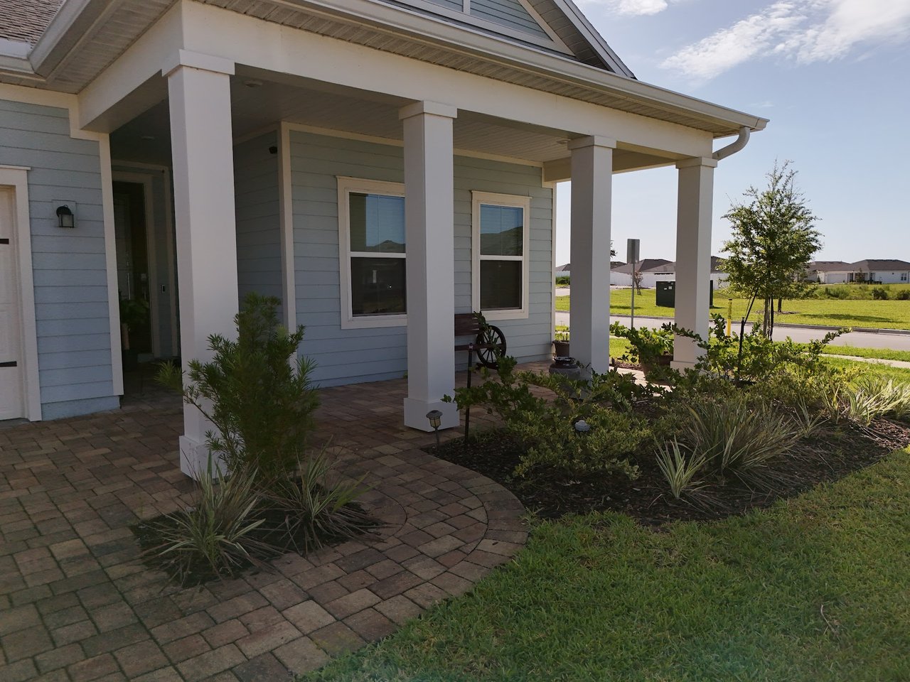 Home with a covered columned porch, curved brick walkway, and landscaped front yard.