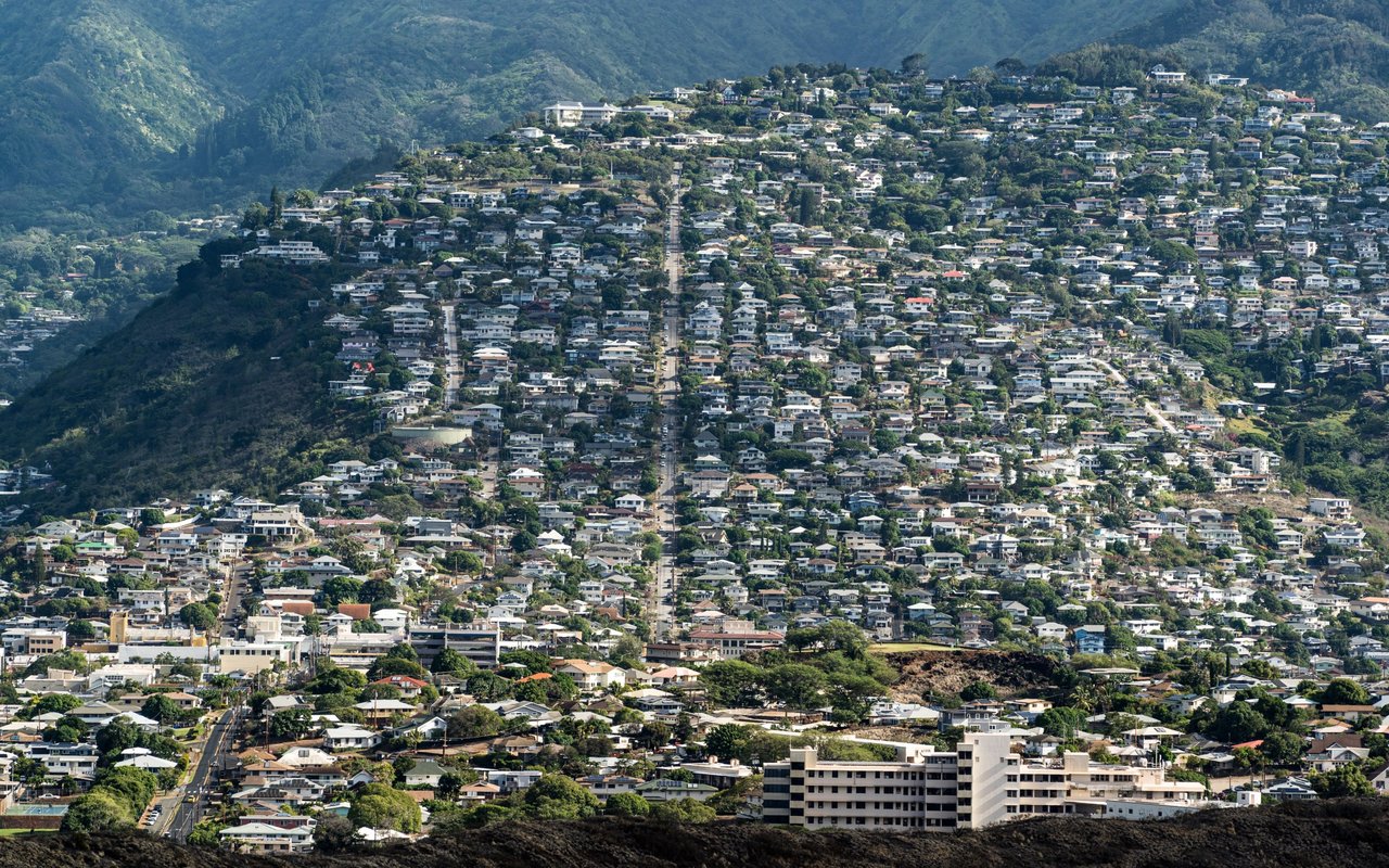 Wilhelmina hillside neighborhood with homes spread across the slopes below green mountains.