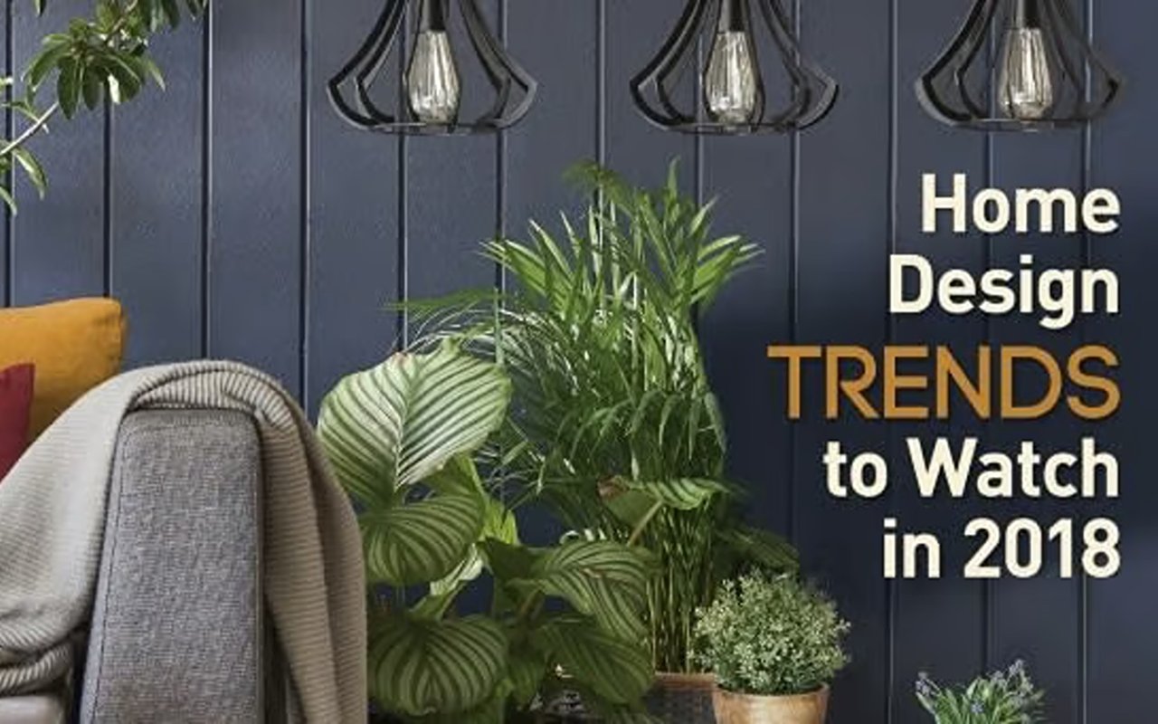 Home design trends to watch in 2018, over a styled room with pendant lights, plants, and an upholstered chair.