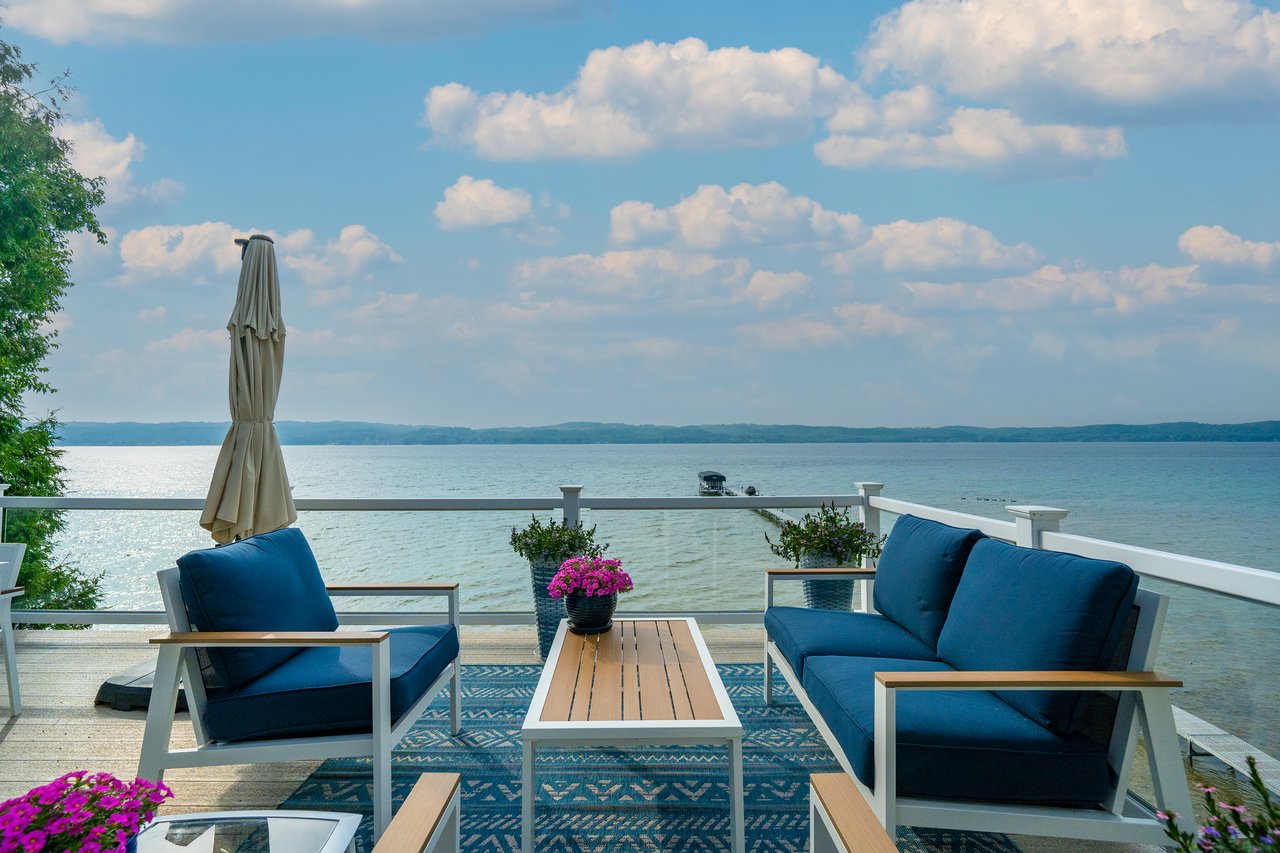 Lakeside deck with blue outdoor seating and flowers overlooking the water.