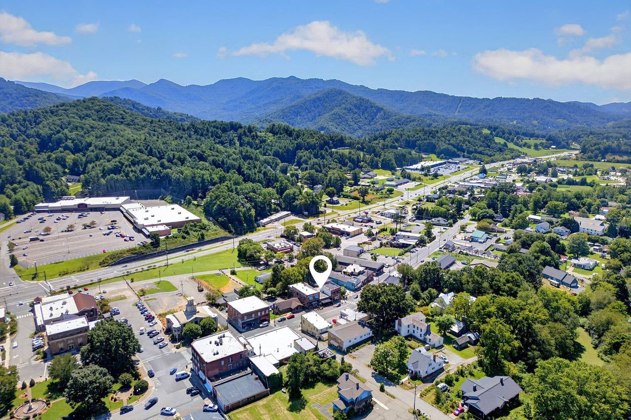 Aerial view of a marked downtown property with surrounding businesses and mountain ridges.