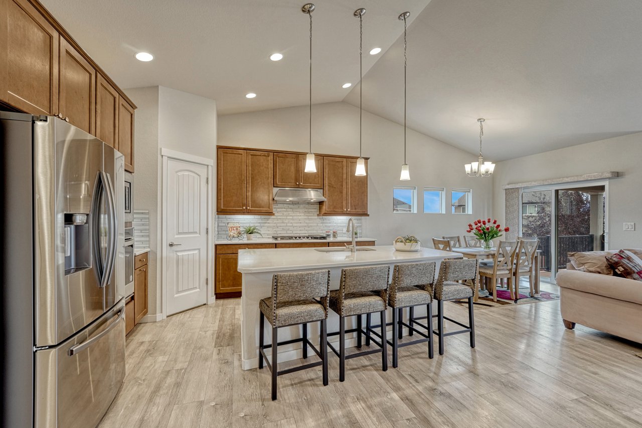 Kitchen with stainless appliances, wood cabinets and a four-seat island under pendant lights