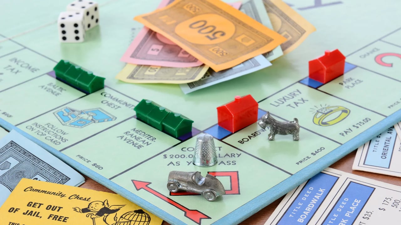 Monopoly board with colorful houses, scattered play money, dice, and metal game tokens.